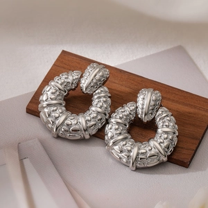 Silver-plated hoop earrings with embossed hammer texture on a wooden background