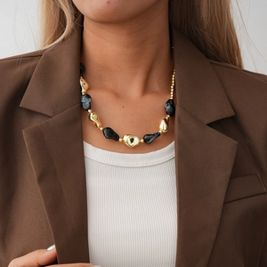 Detail of chunky acrylic irregular bead necklace with golden metal accents on a model