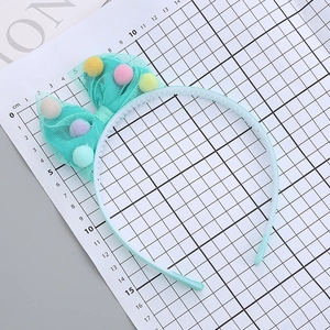 Kids blue princess headband featuring a large green mesh bow with colorful fuzzy balls