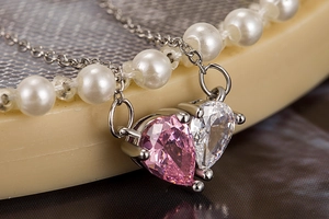 Macro shot of double heart necklace with pink and white pear-cut cubic zirconia stones