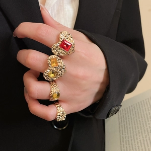 Macro shot of vintage gold rings with heart design and colorful gemstones on model hand