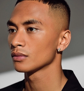 Gros plan d'une boucle d'oreille rectangulaire argent et or sur un modèle homme