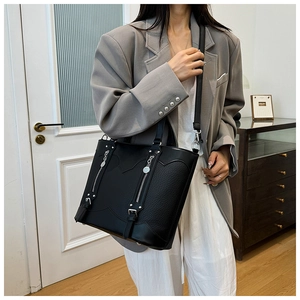Detail of black pebbled leather tote bag with metallic zippers and adjustable strap