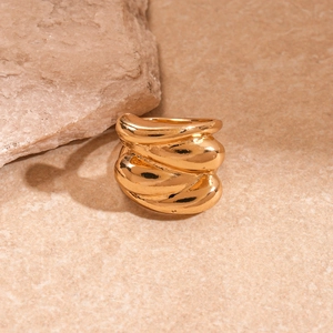 Detail of gold chunky ring with wave texture and metallic mirror finish on natural stone