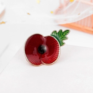 Close-up of red enamel poppy brooch with green leaf and sparkling rhinestone details