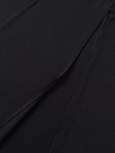 Close-up detail showing the fine stitching and side slit on the black crepe fabric dress