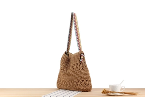 Detail of hand-woven straw beach bag featuring hollow floral pattern and ethnic style strap