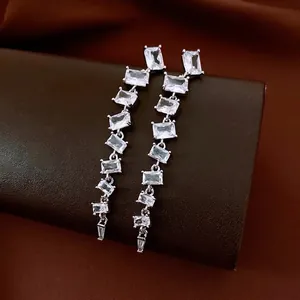 Boucles d'oreilles minimalistes avec zircon carré et glands sur fond de cuir