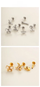 Close-up of stainless steel piercing studs featuring butterfly and daisy zircon designs