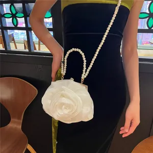 Detailed view of a white camellia bridal clutch featuring a pearl handle and crossbody chain