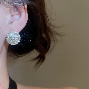 Close-up of a sparkling silver double-layer round stud earring worn by a model