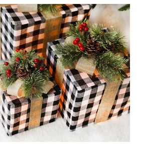 Close-up of buffalo plaid Christmas gift boxes with pine cones and warm glowing lights