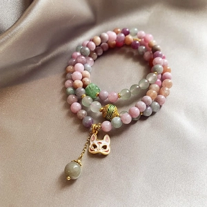 Macro view of multi-layer crystal beads with a cat mask charm on champagne silk