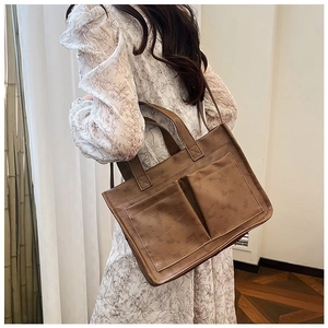 Detail view of brown vintage PU tote bag with two front pockets on a white floral dress