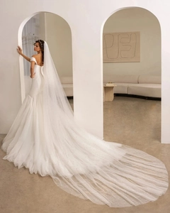 Close-up of off-shoulder satin mermaid wedding dress with long pearl embellished veil