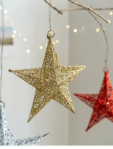 Detail of hollow glitter stars in gold, red and silver for festive window decorations