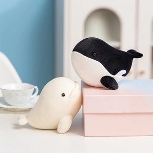 Cute plush whale and orca stuffed animals in a soft pastel gift setting for children