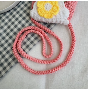 Detail of pink hand-crocheted child purse featuring a 3D knit sunflower and shoulder strap