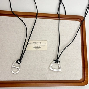 Detail of matte silver flower and geometric pendants with minimalist black cords