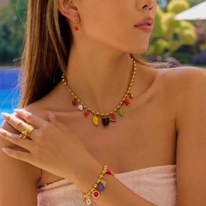 Outdoor close-up of a model wearing 18K gold fruit-themed necklace and jewelry set