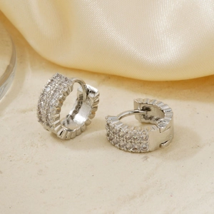 Makroaufnahme von Huggie-Ohrringen mit dreireihigem Zirkonia-Pavé und Wellendetails