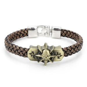 Braided brown leather bracelet with bronze skull head charm on a white background