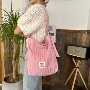 Detail view of pink pleated canvas tote bag featuring a white square fabric label