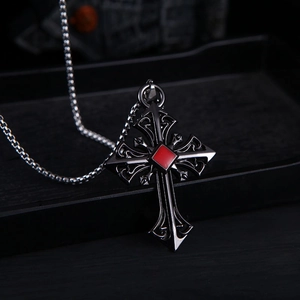 Close-up of retro cross pendant with square red gemstone and vintage hollow patterns