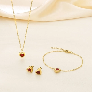 Détail de parure bijoux plaqué or 18k avec pierres cœur rouges sur satin