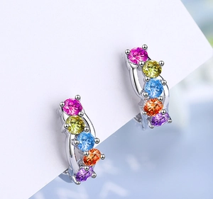 Close-up of silver earrings with colorful round-cut crystals in pink, yellow and blue