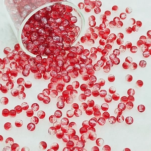 Macro detail of red crackle glass beads spilling from a glass onto soft white fur