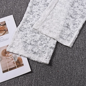 Detailed close-up of white lace fabric featuring intricate hollow floral embroidery patterns