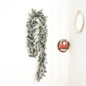 Detail of flocked Christmas garland with snow effect hanging on a white interior wall