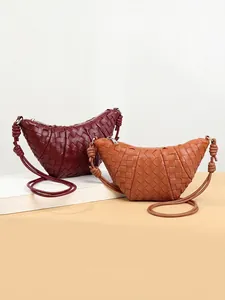 Handwoven croissant shoulder bags in burgundy and tan leather with knotted straps
