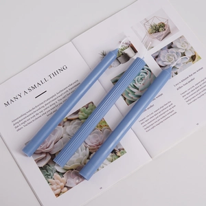 Three elegant blue taper candles with smooth and ribbed textures on a book