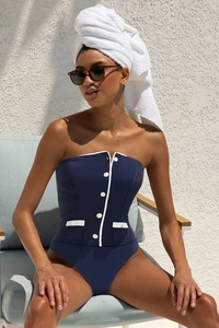 Detail of navy one-piece swimsuit featuring contrast white trim and button accents