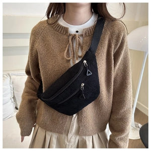 Close-up of black corduroy crossbody bag with double zippers and adjustable strap