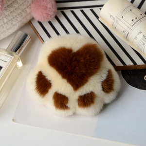 Detail of plush cat paw keychains in white and brown with heart pattern and props
