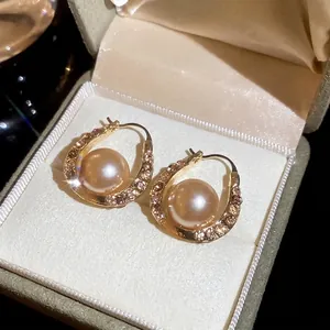 Elegant U-shaped gold earrings featuring sparkling rhinestones and champagne pearls