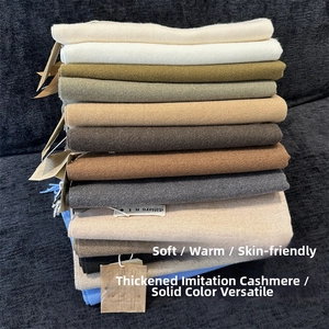 Multiple solid colored cashmere feel scarves stacked showing soft texture and tassels