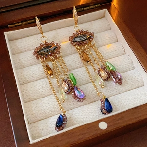 Detailansicht goldener Quastenohrringe mit bunten Zirkonias auf einer Schmuckschatulle