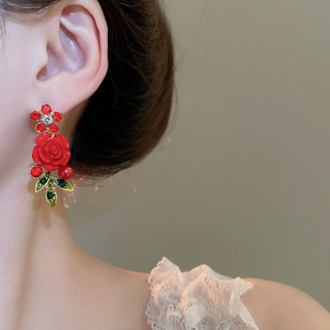 Close-up of red rose earring with rhinestones and green leaves on model