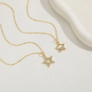 Detailed close-up of two gold necklaces with sparkling star pendants and zircons
