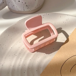 Detailed view of a matte pink square hair claw clip on a stylish ceramic plate