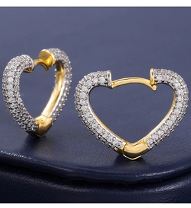 Macro shot of two-tone heart earrings with pave-set zircon on premium leather background