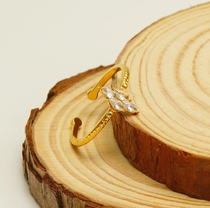 Detail of a gold adjustable ring with four marquise-cut zircons on a rustic wood base
