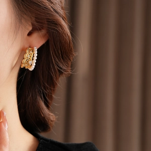 Detail view of pearl lace earring with gold filigree and zircons on model ear