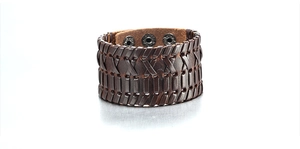 Detailed close-up of a dark brown braided leather cuff bracelet with metal snap fasteners