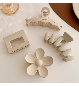 Detail view of a 4-piece set of matte cream hair claws in various geometric shapes