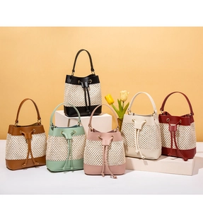 Multi-color straw and leather bucket bags displayed on geometric stands in six colors